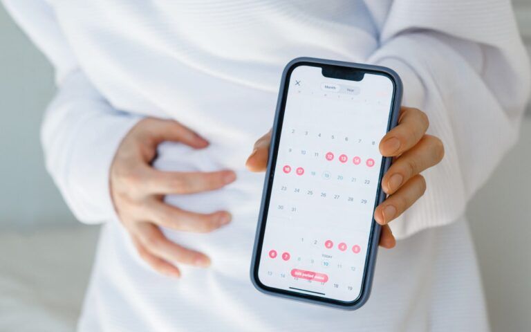 Woman Holding Phone Showing Calender For Tracking Periods